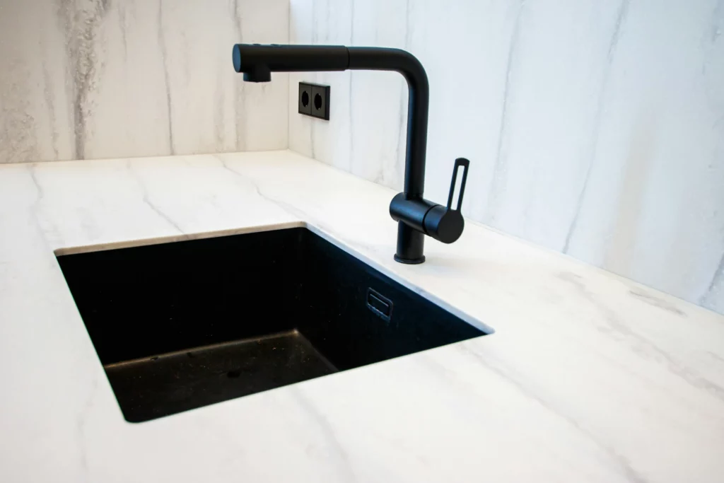 Black faucet over an undermount sink in a marble countertop