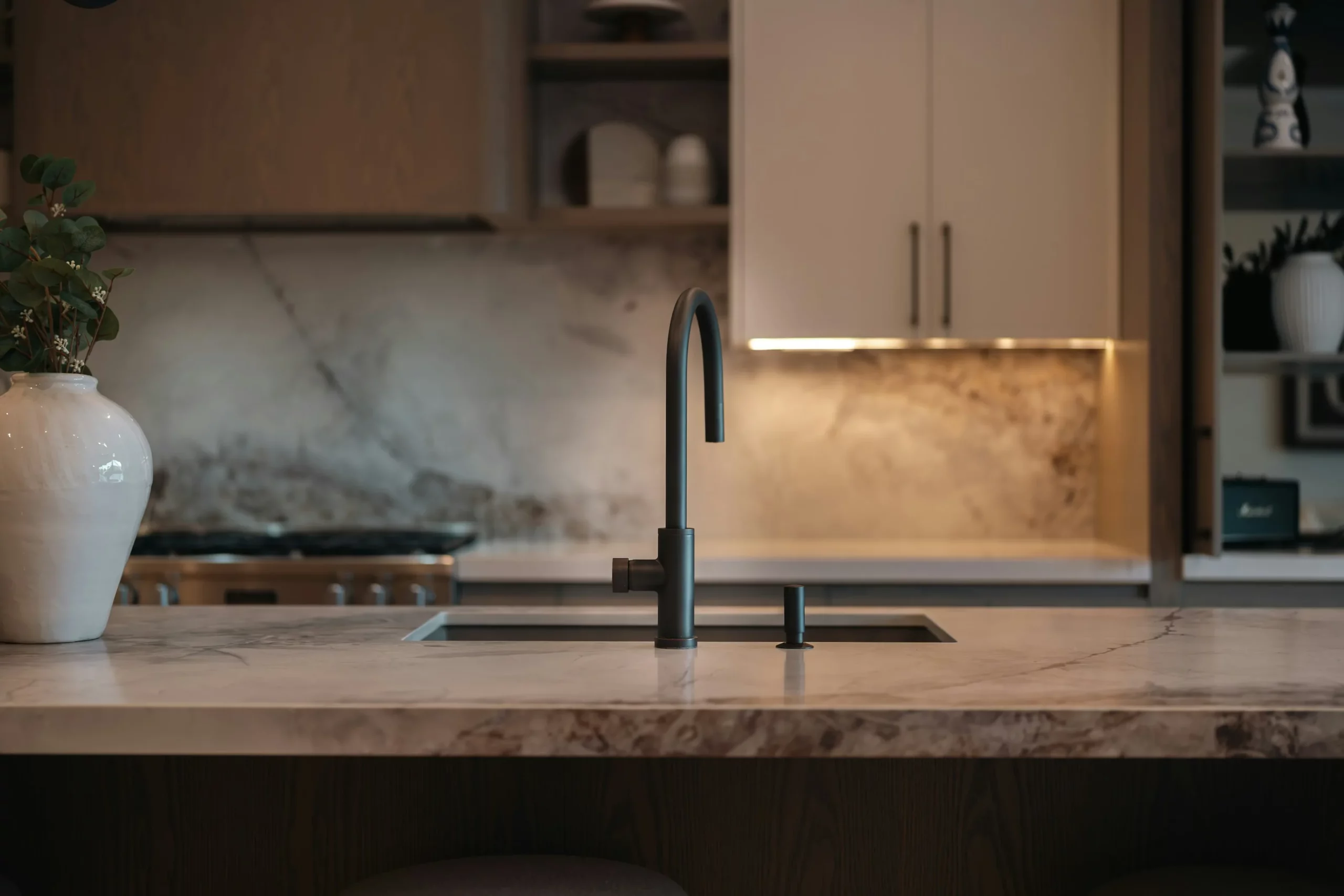Marble island and slab backsplash with a black faucet