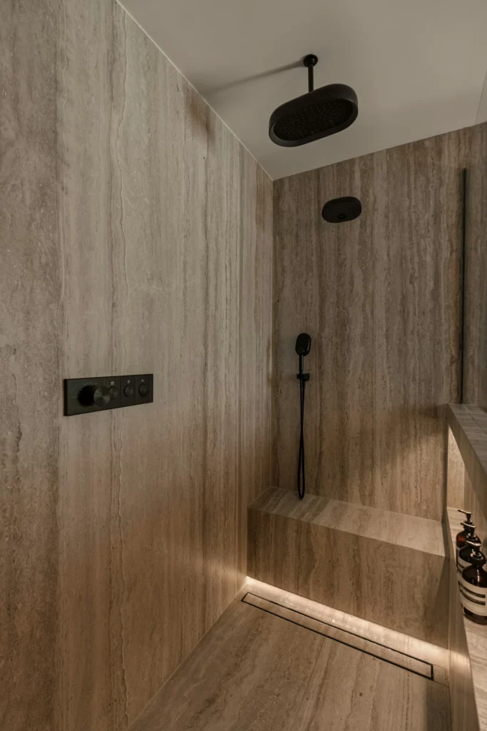 Floor-to-ceiling stone slab shower with a rain head